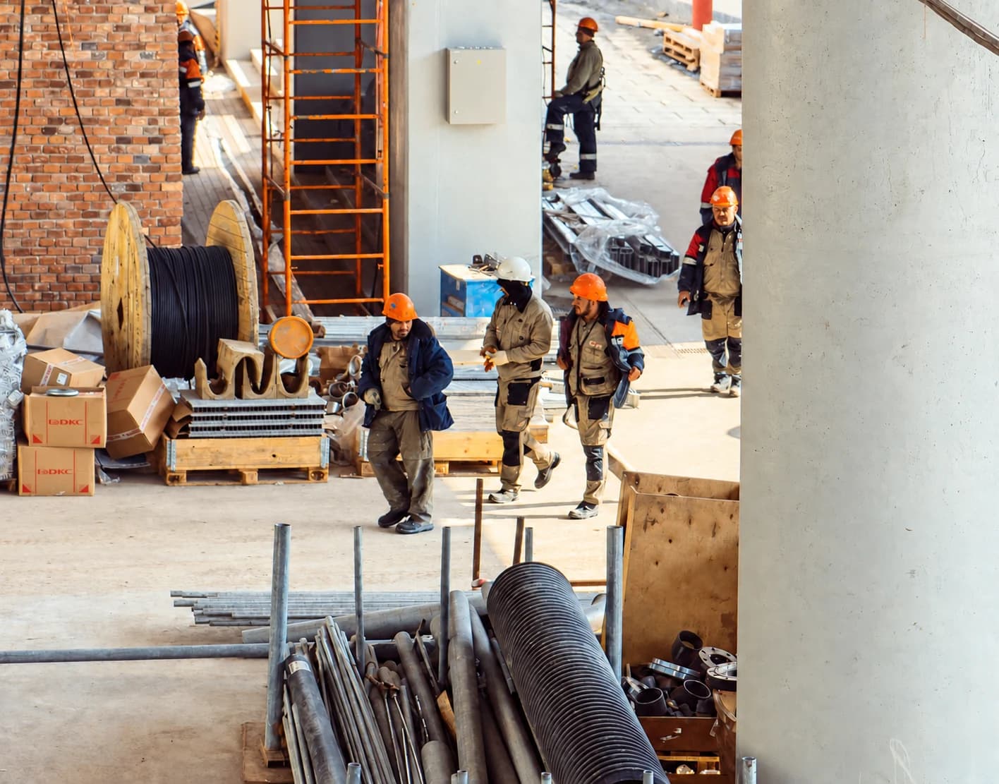 Construction workers in hard hats walking through an unfinished building.