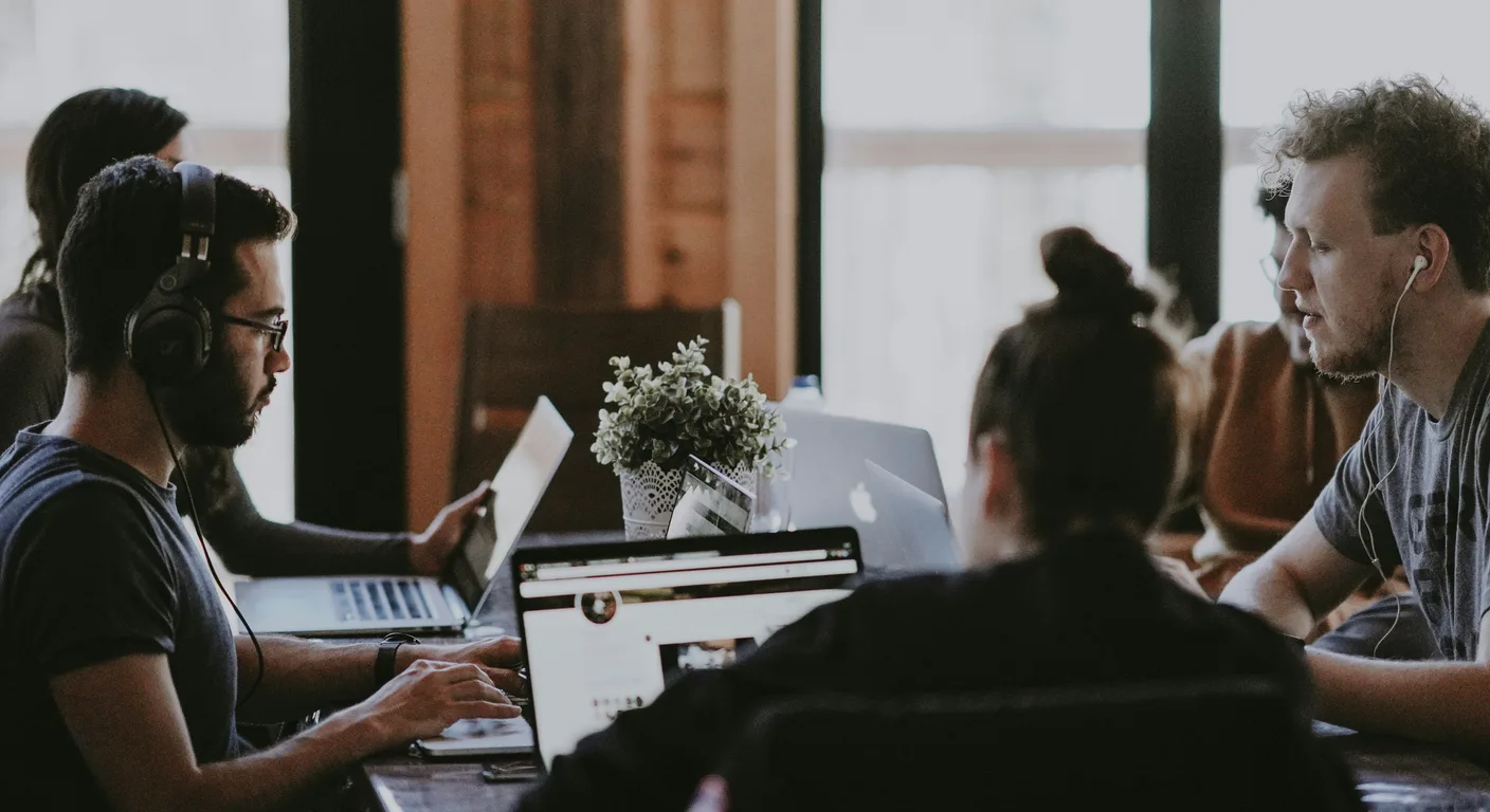 Colleagues working together around a table with laptops